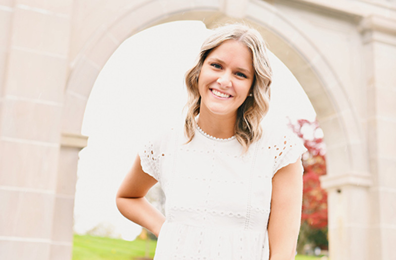 A young woman standing in front of the Marywood Arch.